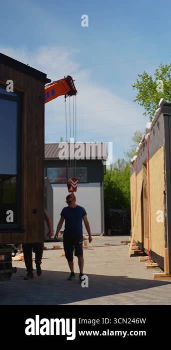 Construction workers carefully unloading prefabricated tiny house
