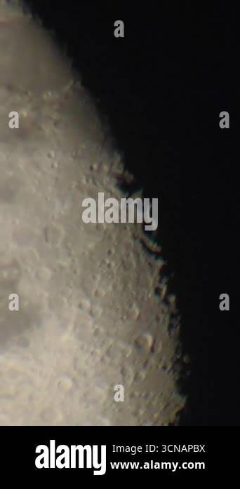 Vertical close-up shot through a telescope pans across the moons ...