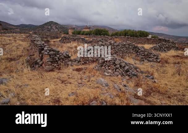 Remnants of ancient stone walls lay across a dry, golden landscape with ...