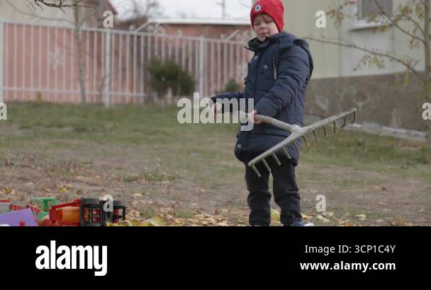 Boy Rakes Leaves in Backyard. Cold Autumn Weather Slow motion 4K 10-bit ...
