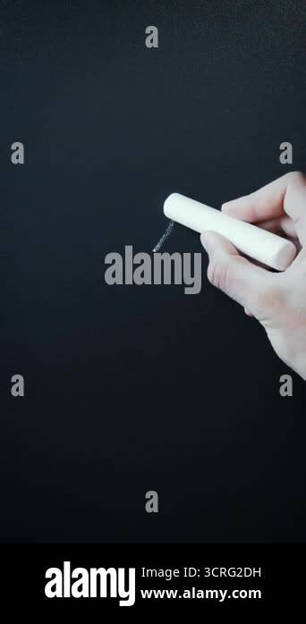 Writing mathematical formulas on dark black chalkboard. Hand writes ...