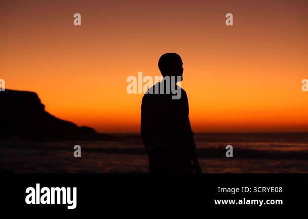Silhouette view of a man celebrating success at seaside at sunset in ...