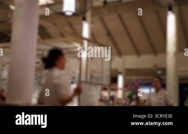 Two waitresses interact in a bustling restaurant, showcasing a lively ...