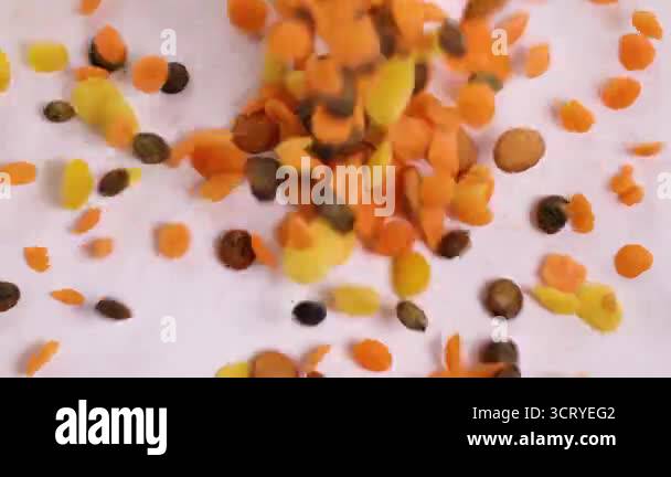 Vibrant lentils and chickpeas cascade onto a surface, creating a ...