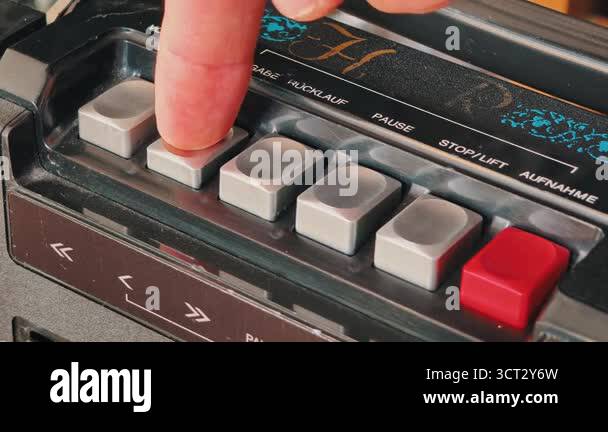 Macro close-up shot of finger pressing play button on vintage cassette ...