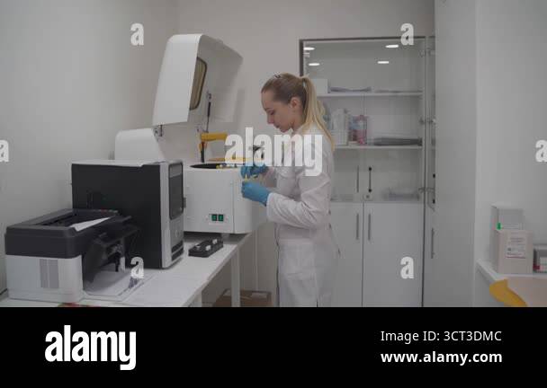 Lab technician in uniform places blood samples into automated robotic ...