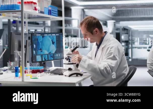 Male science expert operates with microscope and laboratory tray ...