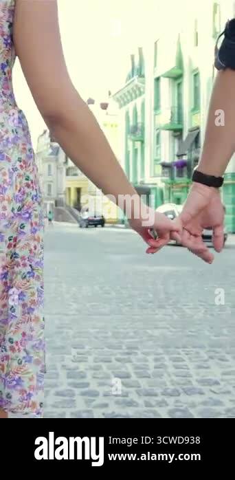 A joyful couple strolls hand in hand along a picturesque cobblestone ...