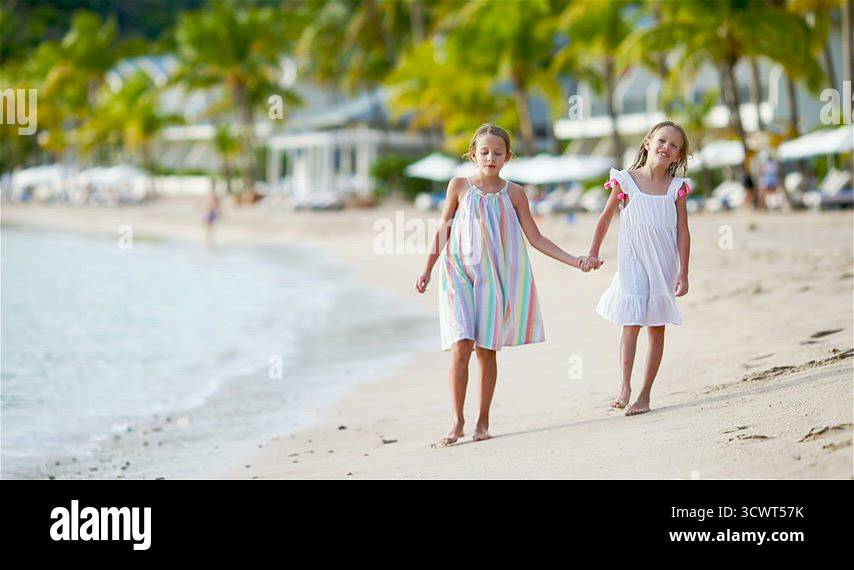 Adorable little girls walking on the beach and having fun together ...