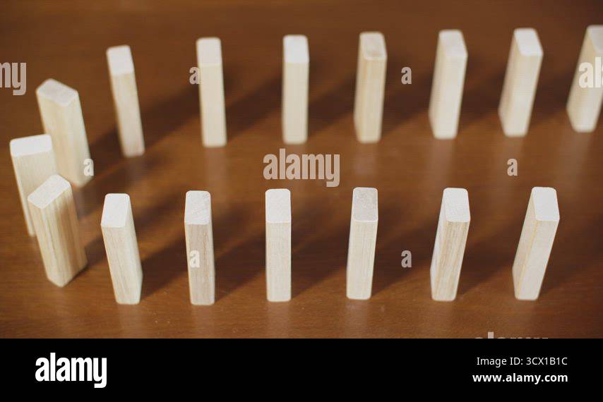Close up row white dominoes falling on wooden surface. Concept business ...