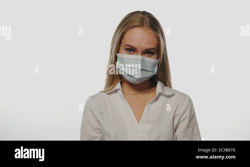 Dark blond haired nurse in a medical mask shows indifference or ...