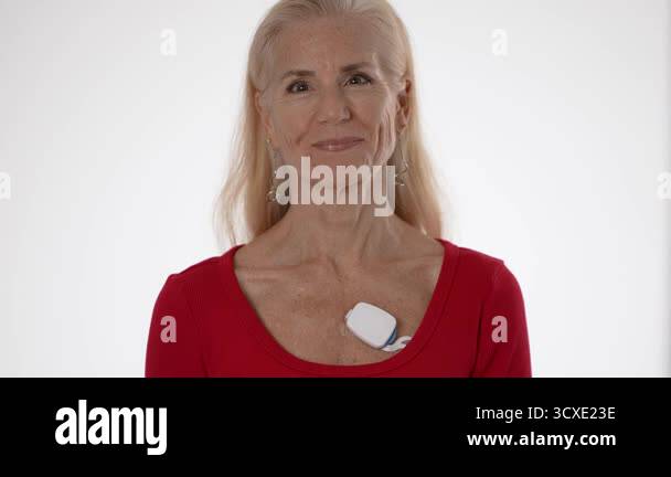 A mature woman with a joyful expression wears a heart sensor on her ...