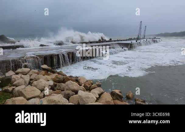 Massive storm waves crashing over a pier with seawater flooding the ...