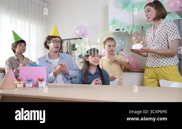 Clapping Cake Asian girl receive cake while making a wish and blowing birthday candle ...