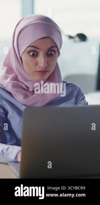 A young woman dressed in a beautiful hijab is deeply focused on her ...