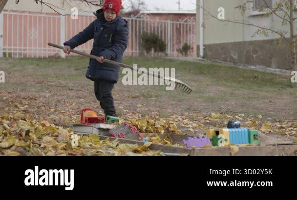 Boy Rakes Leaves in Backyard. Cold Autumn Weather Slow motion 4K 10-bit ...