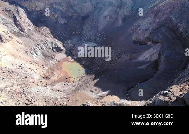 Drone footage slowly flying over a dormant volcano crater with a small ...