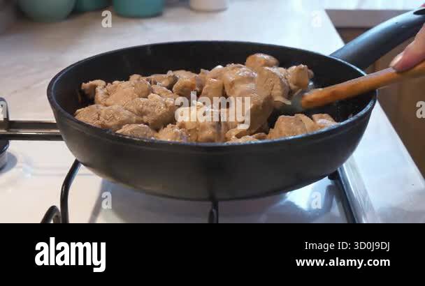 Frying meat. Cook stirs pieces of meat with onion in frying pan on a ...