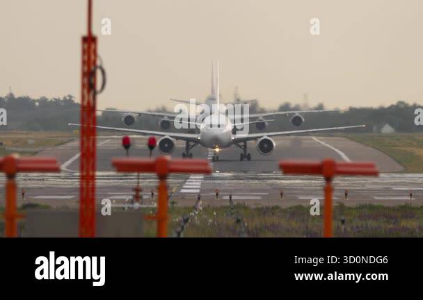Two unbranded passenger jets taxi in sequence on the runway, front view ...
