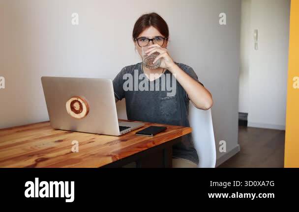 A Healthy Habit. Woman Drinking Water While Working on a Laptop. A ...