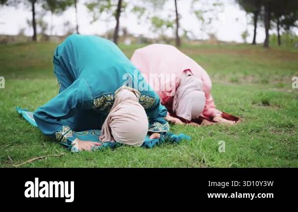 Two devout muslim women wearing traditional hijabs performing the salah ...