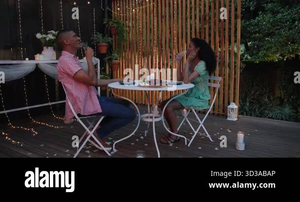 Laughing and sharing, diverse couple having romantic dinner in garden ...