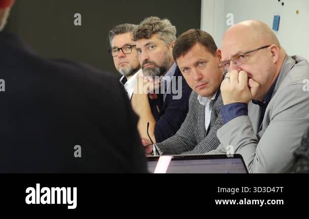 Valmiera, Latvia - October 17, 2025: Four men are deeply engaged in ...
