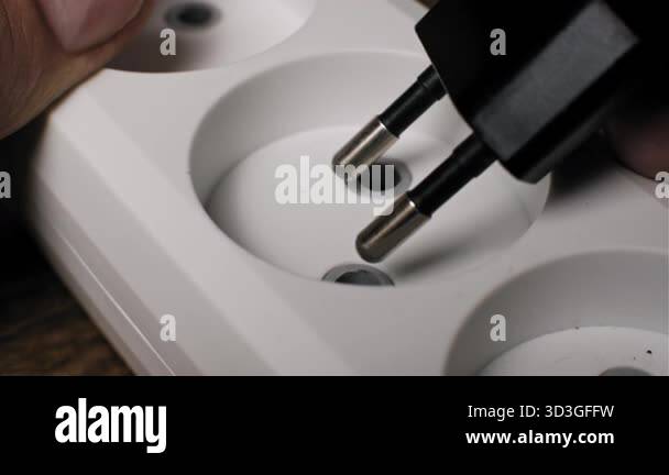 Extreme close up of a male hand inserting a black power plug into a ...