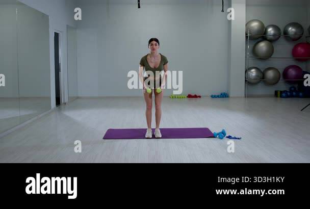 athletic woman focuses on her form while doing a bent over dumbbell ...