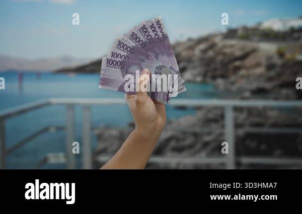 Man holding indonesian rupiah banknotes at seaside, showcasing money ...