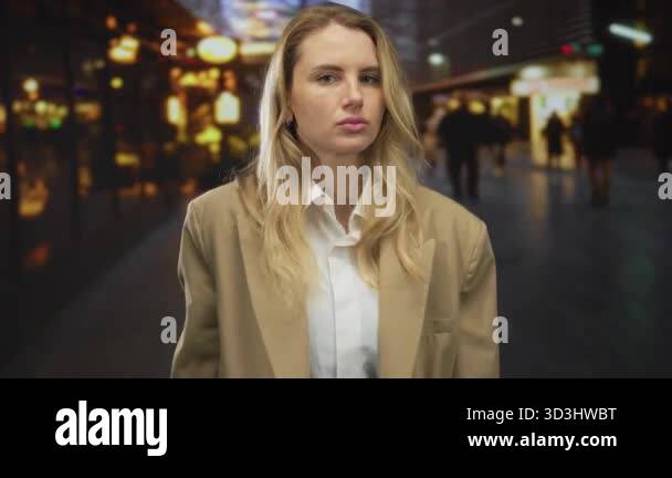 Woman with blonde hair making a stop gesture on a busy city street at ...