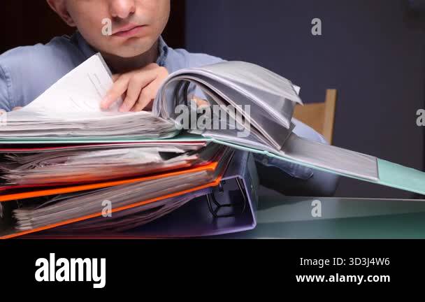 Man searching through ring binders at a cluttered desk, sifting ...
