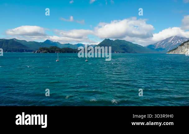 Two sailboats navigating the beautiful turquoise waters of a vast bay ...