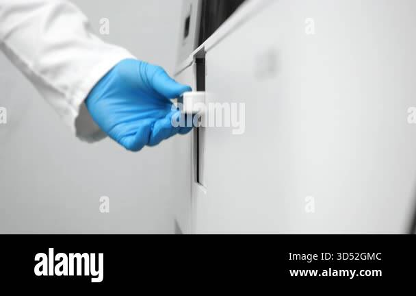 Medical professional wearing blue gloves inserting rack with test tubes ...