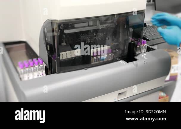 Laboratory technician placing blood test tubes into modern automatic ...