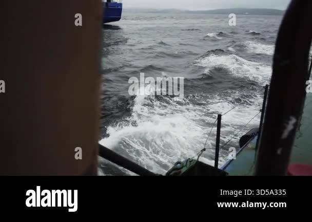 Massive ocean waves rise and fall rhythmically around cargo ship ...