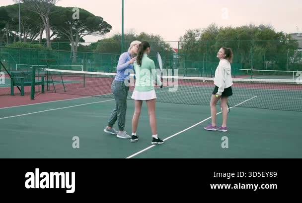 Adjusting grip, coach and students practicing racket swings celebrating ...