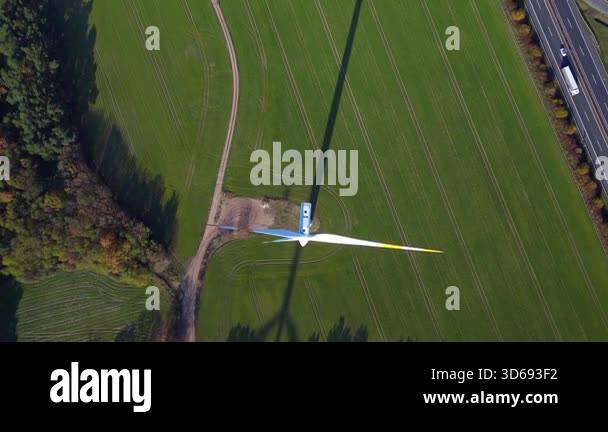 Wind turbine shadow standing in green field next to highway autobahn in ...