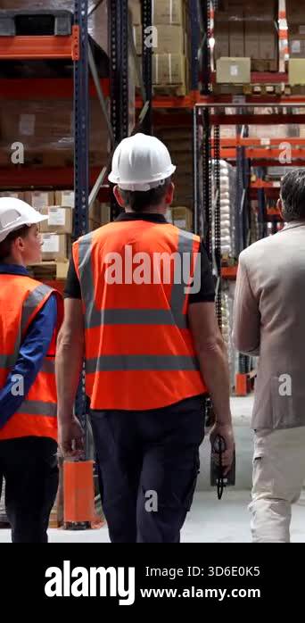 Diverse team of warehouse workers and their manager walking through a ...