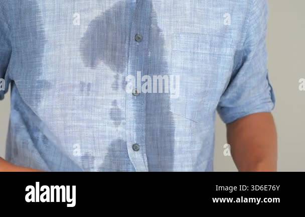 a-man-demonstrates-noticeable-sweat-stains-on-his-blue-shirt-after
