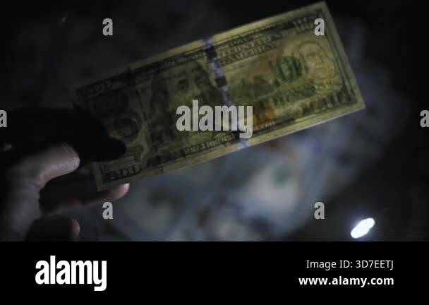 Close up of a hand inspecting a one hundred dollar bill for ...