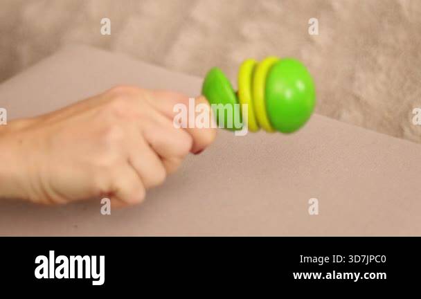 A person shakes a colorful wooden rattle in their hand, creating loud ...