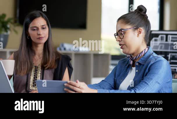 Reaching for tablet starting discussion Diverse female colleagues ...