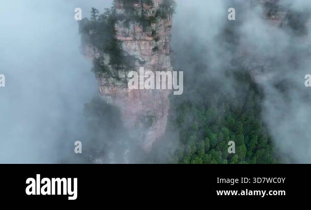 Sheer vertical cliff faces and rock pillars shrouded in mist and low ...