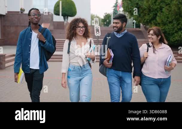 Cheerful group of four multi ethnic university students walking ...