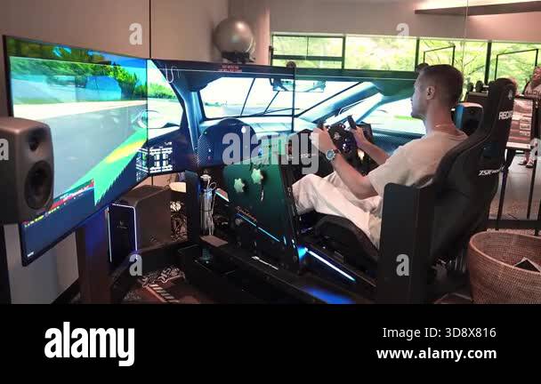 A man grips a force wheel in a TSK Racing rig with Recaro seat, triple ...