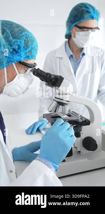 Two scientists in lab coats, face masks, and protective glasses ...