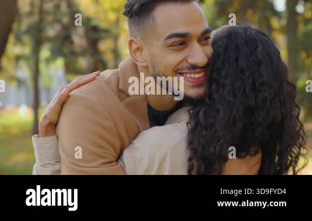 Portrait Hispanic man hugging unrecognizable woman in autumn park ...