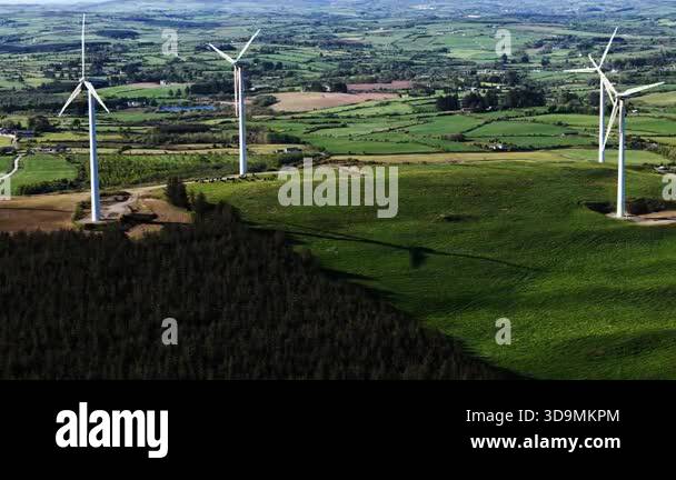 Several wind turbines stand tall on a grassy hill in the Irish ...