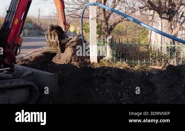 Excavator engages in digging soil from a trench, demonstrating ...
